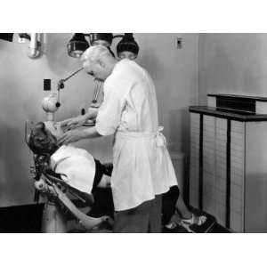 Dentist Examining Female Patient in Chair of Dental Office 