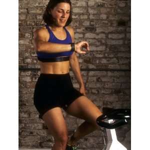  Young Woman Exercising on a Stationary Bike Checking her 